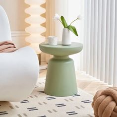 a white chair sitting next to a table with a vase on it