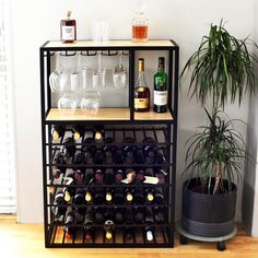 a wine rack with several bottles and glasses on it next to a potted plant