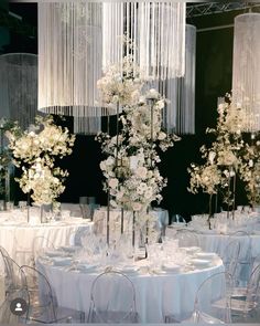 a tall vase filled with white flowers sitting on top of a table covered in chairs