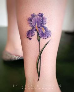 a purple flower tattoo on the leg