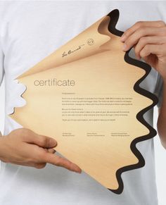 a person holding a piece of wood with the word certificate printed on it, in front of their hands