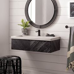 a bathroom sink sitting under a round mirror next to a black and white rug on the floor