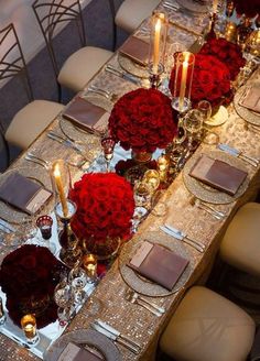 the table is set with red roses and silver place settings for an elegant dinner party