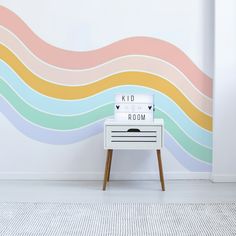 a room with a wall painted in pastel colors and a white table on the floor