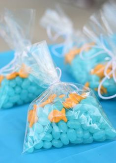 some bags filled with blue and yellow candies on top of a table next to a red car