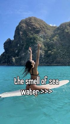 a woman on a surfboard in the water with her arms up and hands raised