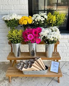 flowers are arranged in metal buckets on a wooden stand with a sign that says welcome