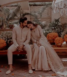 a man and woman sitting on a bench in front of flowers