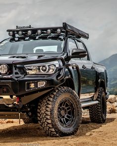 a black truck parked on top of a dirt field