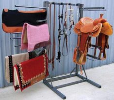 there are many different types of saddles hanging on the rack in front of a building