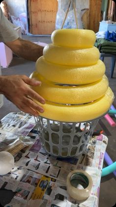 a person is making a cake with yellow icing on the top and around it