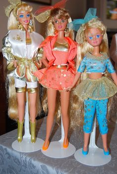 three barbie dolls standing next to each other on a table