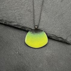 Steel, vitreous enamel in a vibrant yellow-green and oxidized sterling silver come together to create this unique necklace. Pendant is 1 inch in length and the chain is adjustable between 16 and 18 inches. Handmade in San Francisco, CA. Green Oxidized Pendant Necklace, Green Enamel Jewelry With Black Enamel, Modern Green Enamel Jewelry, Green Jewelry With Black Enamel For Gift, Green Jewelry With Black Enamel As A Gift, Unique Black Enamel Pendant Necklace, Hand Painted Green Modern Jewelry, Modern Hand Painted Green Jewelry, Green Enamel Pendant Necklace