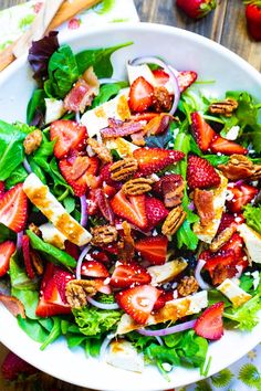 a salad with strawberries, onions and pecans