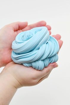 a hand holding a small blue object in it's palm, against a white background