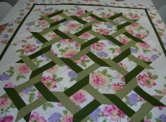 a quilted table topper with flowers on it and green trimming around the edges