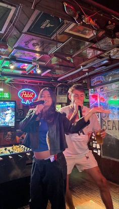 two people singing into microphones in a bar