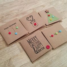 four christmas cards with buttons on them sitting on a wooden table next to each other