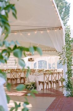 the inside of a tent with tables and chairs set up for an outdoor wedding reception