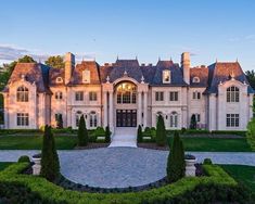 a large white house surrounded by hedges and trees