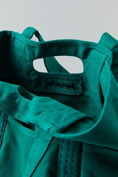 a green tote bag sitting on top of a white wall