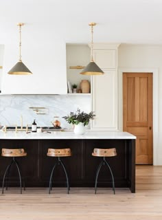 a kitchen with two stools in front of an island and marble counter tops on the wall