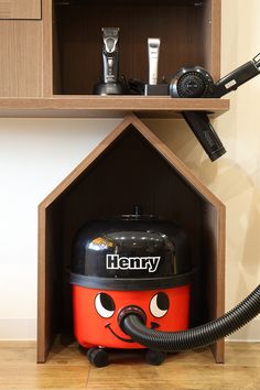 a red and black vacuum sitting inside of a wooden shelf