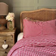 a red and white checkered comforter on a bed next to two nightstands