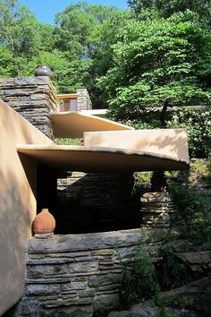 a stone building with a vase in the foreground and trees in the back ground