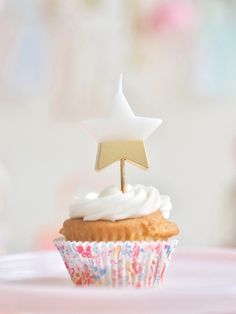 a cupcake with white frosting and a gold star on top