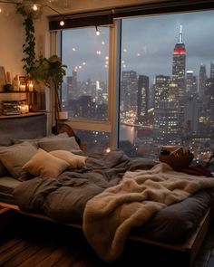 a bedroom with a large window overlooking the city lights and skyscrapers in the distance