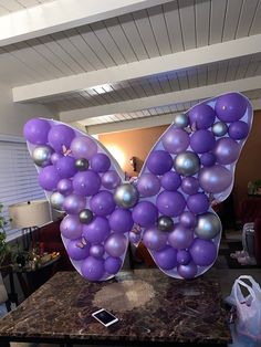 a large butterfly made out of balloons sitting on top of a marble table next to a cell phone