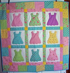 a quilted wall hanging with dresses on it