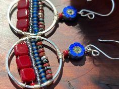 "Silver plated round 1\" hoops with horizontal lines of dark crimson/burgundy glass squares, 8/0 seed beads, deep blue and red and black mottled Picasso seed beads wire wrapped to the hoops. A silky sapphire blue carved glass flower bead lies at the top. Sterling ear hooks. 2 1/4\" x 1\". Matches the Crimson Blues Blossom Bracelet https://etsy.me/38sphwY" Bohemian Red Metal Hoop Earrings, Red Bohemian Small Hoop Earrings, Bohemian Red Small Hoop Earrings, Red Wire Wrapped Hoop Earrings, Red Bohemian Circular Jewelry, Lapis Lazuli Jewelry, Bali Silver, Earrings Wire, Horizontal Lines