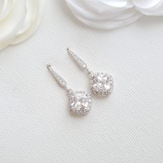 pair of diamond earrings on white fabric with flower