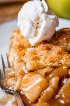 a piece of apple cobbler with ice cream on top and fork in the foreground