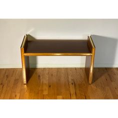 a wooden bench sitting on top of a hard wood floor next to a white wall