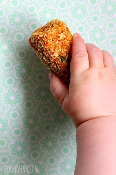 a hand holding a piece of food in it's left hand on a green and white background