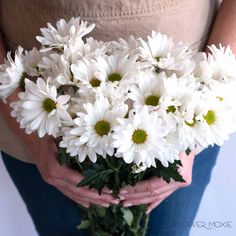 a woman holding a bouquet of white daisies