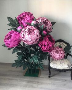 pink flowers are in a vase next to a chair