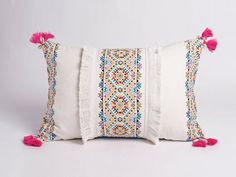 a white pillow with pink tassels on it