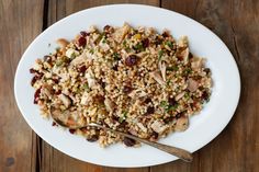 a white plate topped with rice covered in meat and veggies next to a spoon