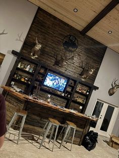 a man standing in front of a bar with deer heads on the wall