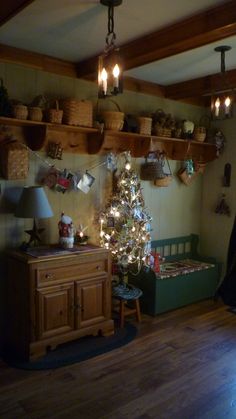 a christmas tree is lit up in the corner of a room with shelves and baskets on the wall