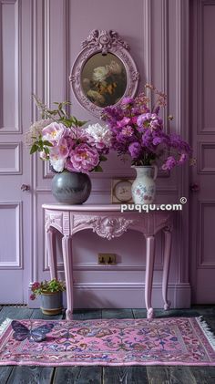 a pink table with vases and flowers on it in front of a purple wall