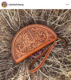 a brown leather purse sitting on top of dry grass