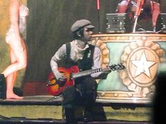 a man sitting on top of a bench while holding a guitar in front of him