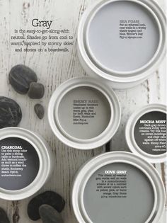 an advertisement for gray paint on a white wooden table with black rocks and pebbles in the background