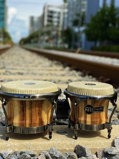 two conga drums sitting on top of train tracks