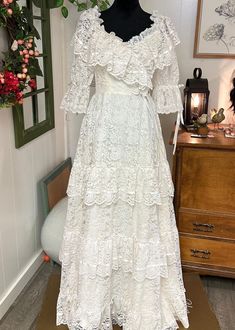 a white dress is on display in a room with flowers and other things around it